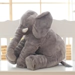 Cuddly toy of a sitting grey elephant. He has big ears and tusks. The cotton plush is soft.