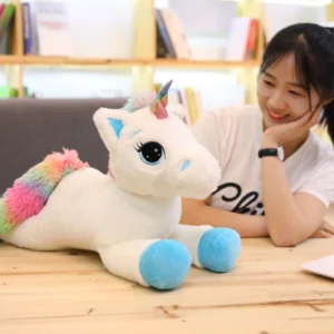 Blue rainbow unicorn plush on a table with a woman