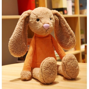 Soft plush rabbit with big ears sitting on a table in front of a piece of furniture