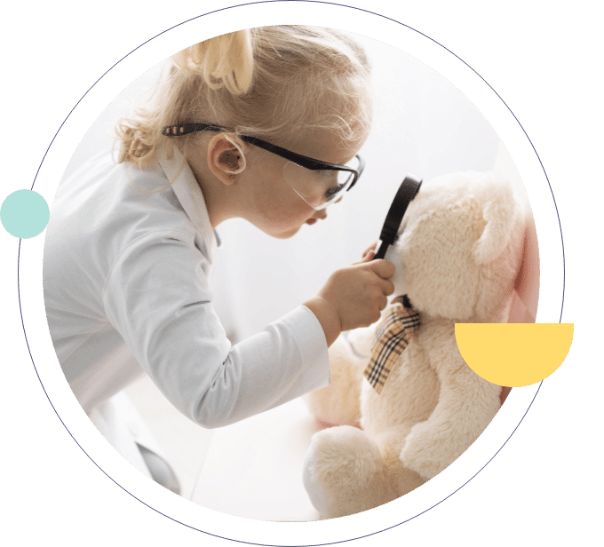 Little girl examining her teddy bear with a magnifying glass