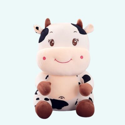 Black and white embroidered baby cow plush on plain background.