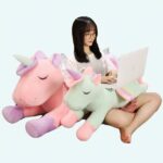 Unicorn plush cushion on a woman with computer in bed