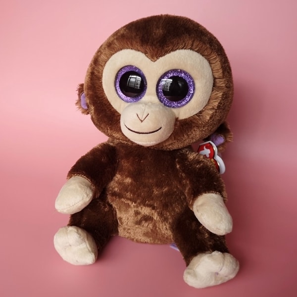 Small brown monkey plush on pink background