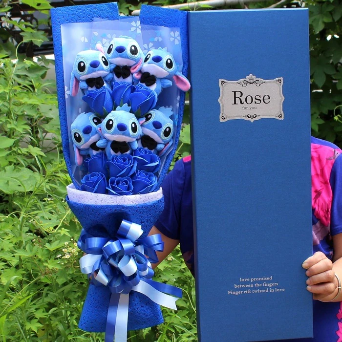 Bouquet of flowers with plush blue gentleman Stitch in front of a tree