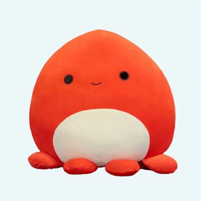 Soft octopus pillow orange on a bed