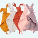 Five bunny cuddly toys in different colours put together on a light coloured fabric