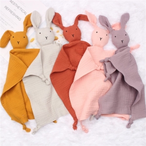 Five bunny cuddly toys in different colours put together on a light coloured fabric