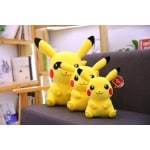 three pikachu plushies sitting one in front of the other on a grey sofa