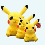 three pikachu plushies sitting one in front of the other on a grey sofa