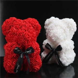 Two teddy bears made of artificial flowers, one is red and the other is white, they are in a black room