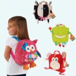 A girl with a pink plush owl backpack and three other plush backpacks with a cow, a frog and a red monkey