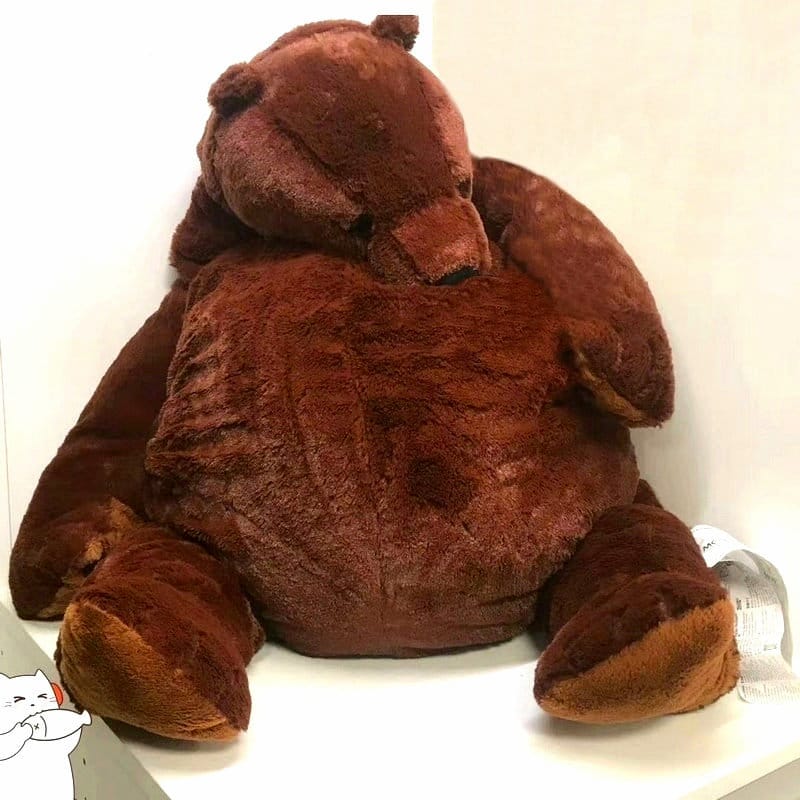 A huge, soft-looking teddy bear sitting in a bright room