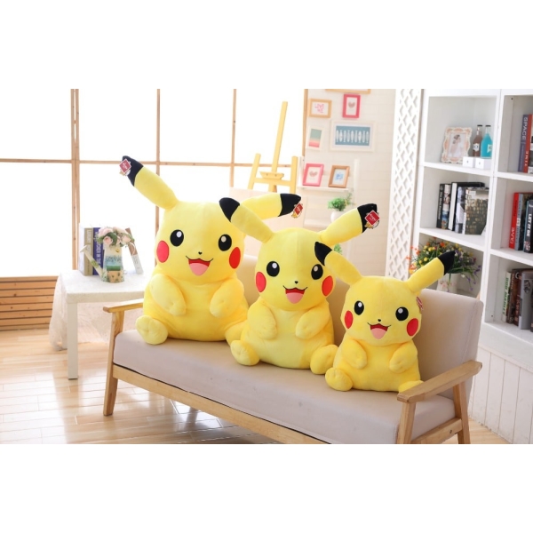 three pikachus of different sizes sitting on a beige sofa in a beautiful room