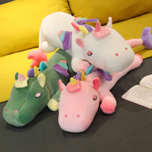3 big unicorn plushies, the two bottom ones are green and pink and the one on top is white, you can see a yellow sofa in the background and they are placed on a black floor