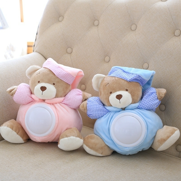 Musical teddy bear white noise with one dressed in blue and the other in pink sitting on a beige sofa
