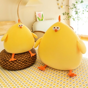 Yellow cushion plush chick sitting on a rattan seat and the other on a yellow and grey patterned floor in front of a white sofa and a plant