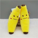 Smiling banana plush against each other against a small wicker basket on a white floor and a grey wall