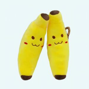 Smiling banana plush against each other against a small wicker basket on a white floor and a grey wall