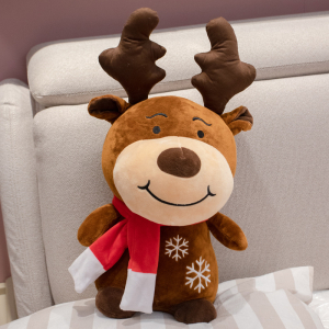 Brown deer plush with red scarf on a grey and white sofa