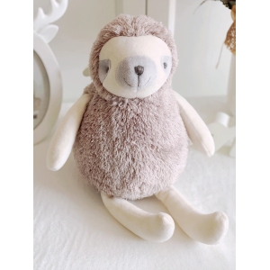 A plush sloth sitting on a beige table, with a grey muzzle and grey eyes.