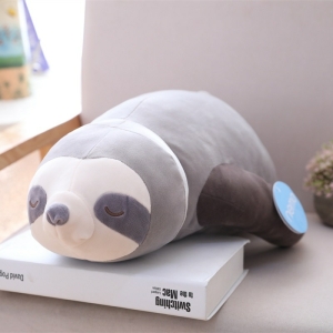 A grey plush pareseux lying on a book on a table, a grey background