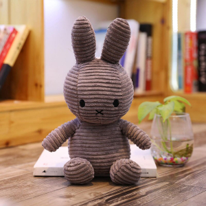 Grey ribbed Miffy plush on a white book, with a background, a shelf with books