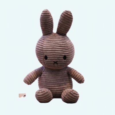 Grey ribbed Miffy plush on a white book, with a background, a shelf with books