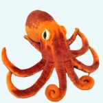 An orange octopus plush on a diamond cushion on a white background.