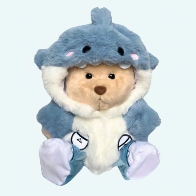 on a light blue background, we see a plush brown bear wearing a blue shark costume