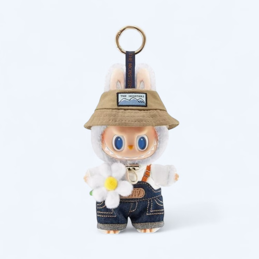 Standing plush with soft cream fur, wearing green overalls with a center pocket, bunny ears, and a mischievous expression, on a neutral background