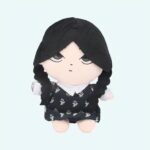 25 cm plush of Wednesday Addams with black braids, a black dress with white flowers, and a stiff white collar. Calm, blank expression. Set against a sky blue background.