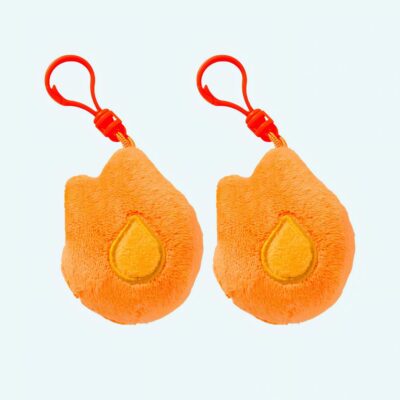 Pair of Duolingo Streak Flame plush toys in soft orange with red keychain hook, on a light blue background.
