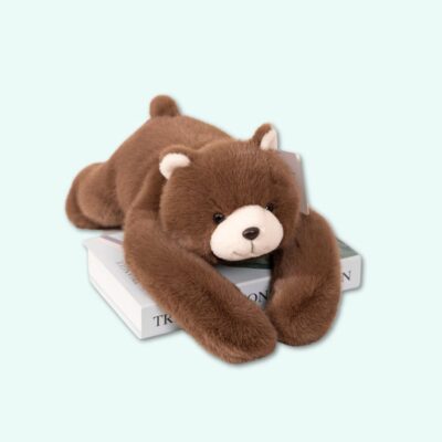 A weighted plush bear with dark brown fur, lying on its belly, on a sky-blue background.