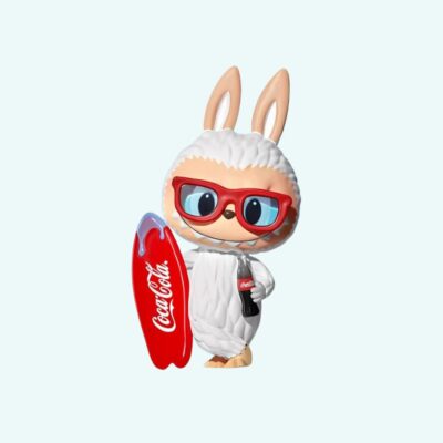 Small kawaii figurine shaped like labubu surfer with a coca-cola bottle on sky blue background.